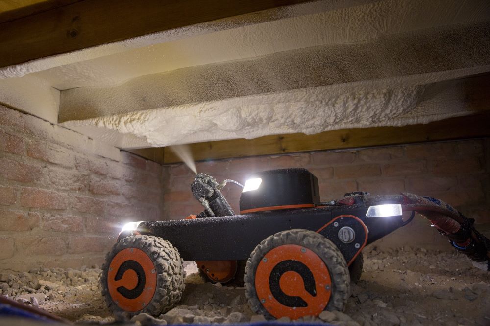 Q Bot robot spraying insulation under floorboards