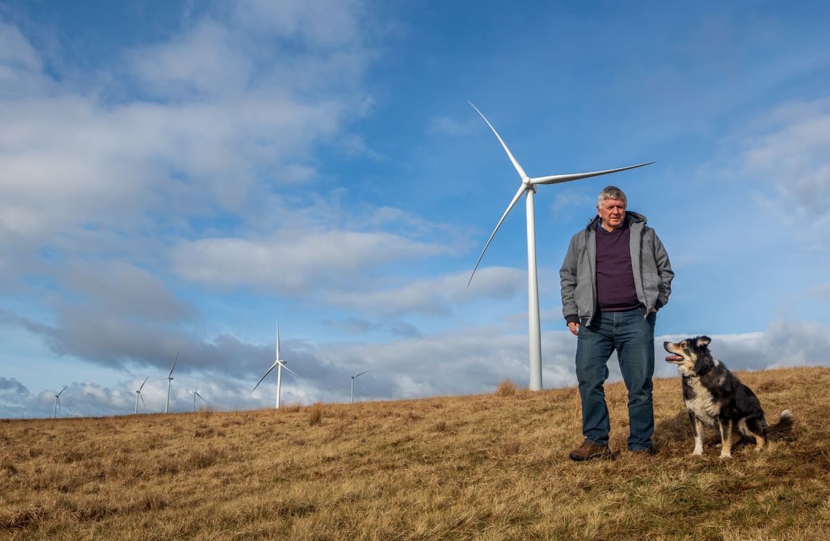 man walking on Welsh moorland with wind turbine in background