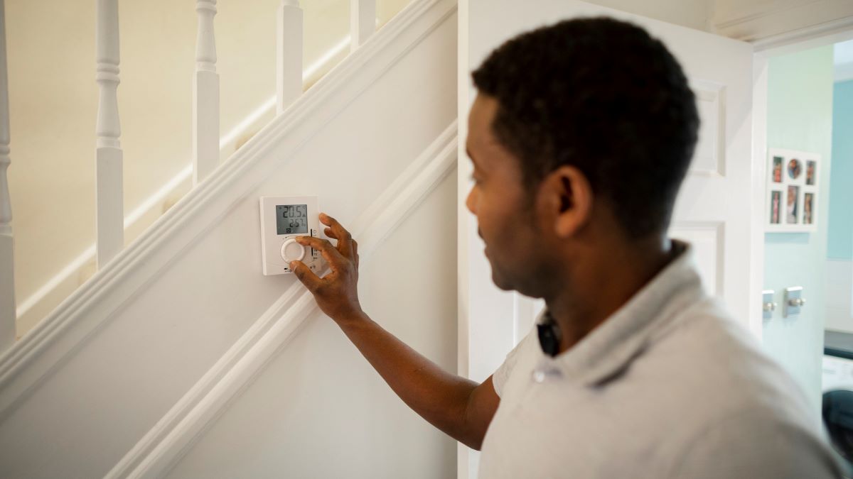 man adjusting thermostat control in home