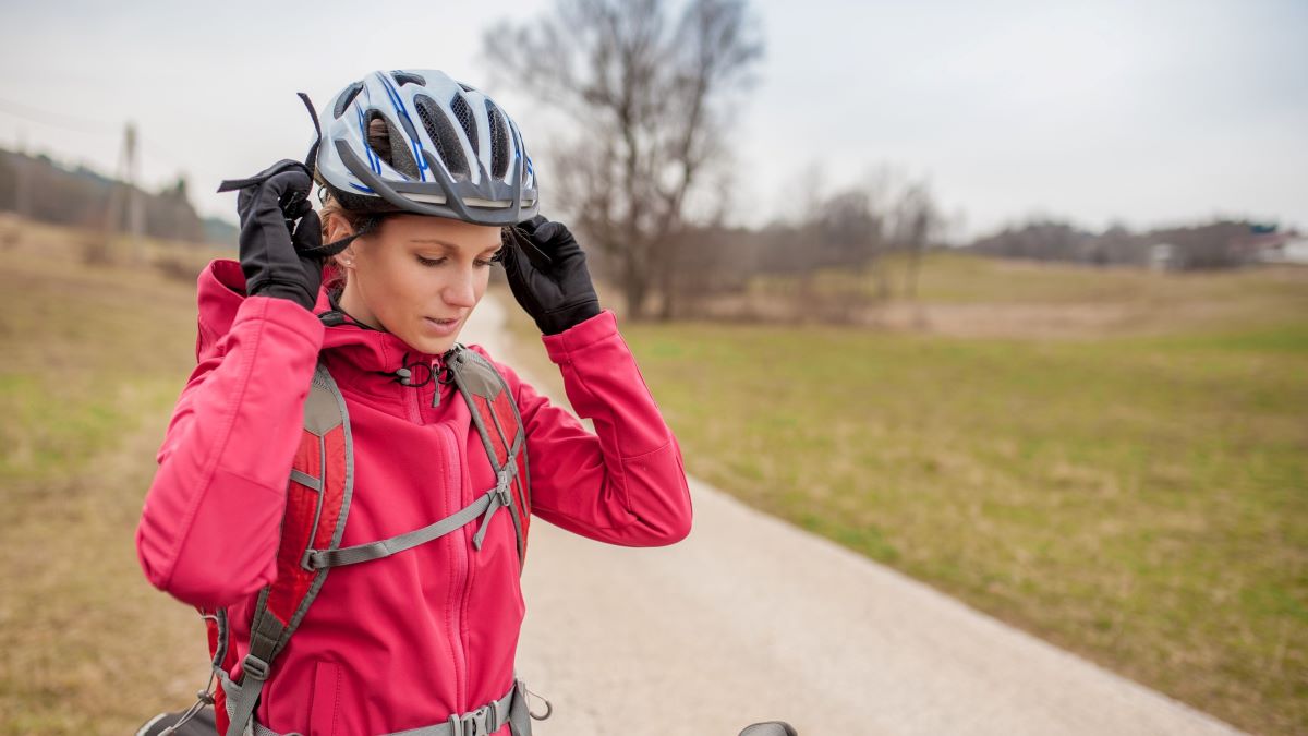 female cyclist putting on helmet
