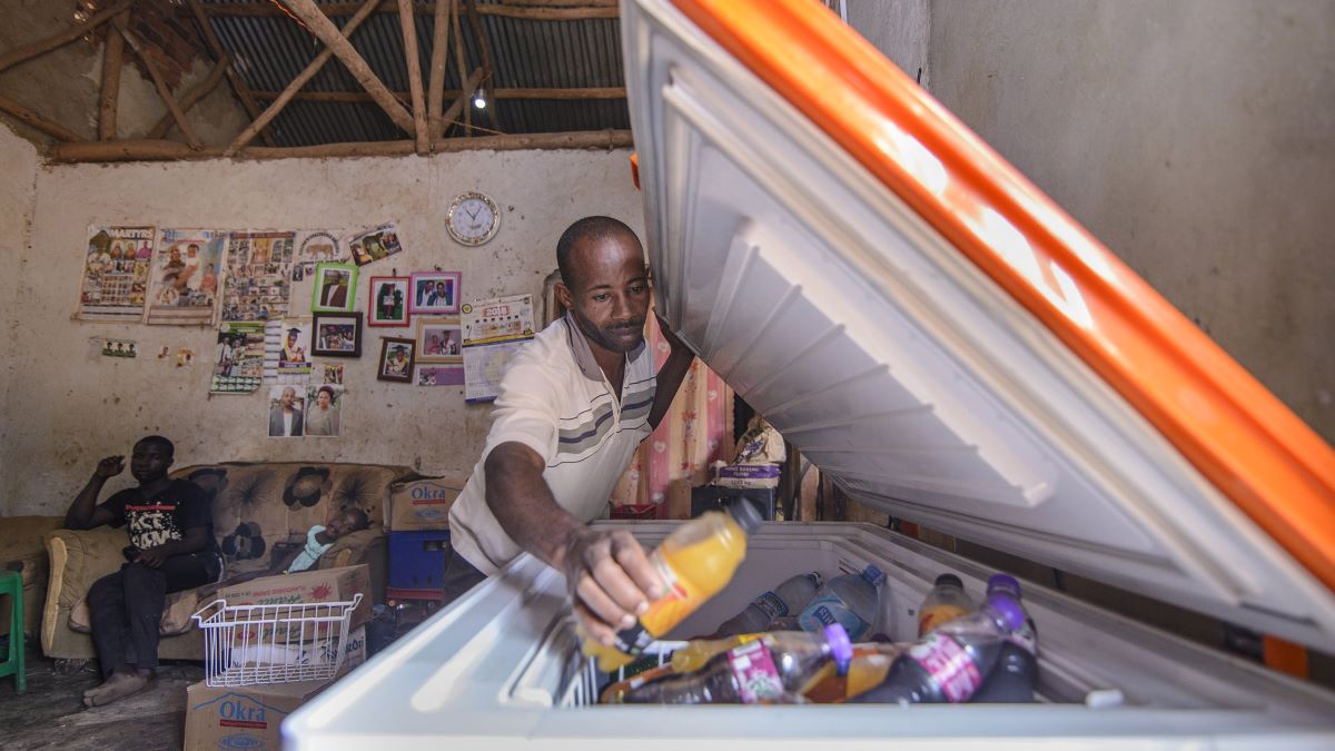 Man opening a fridge in small working area in Uganda