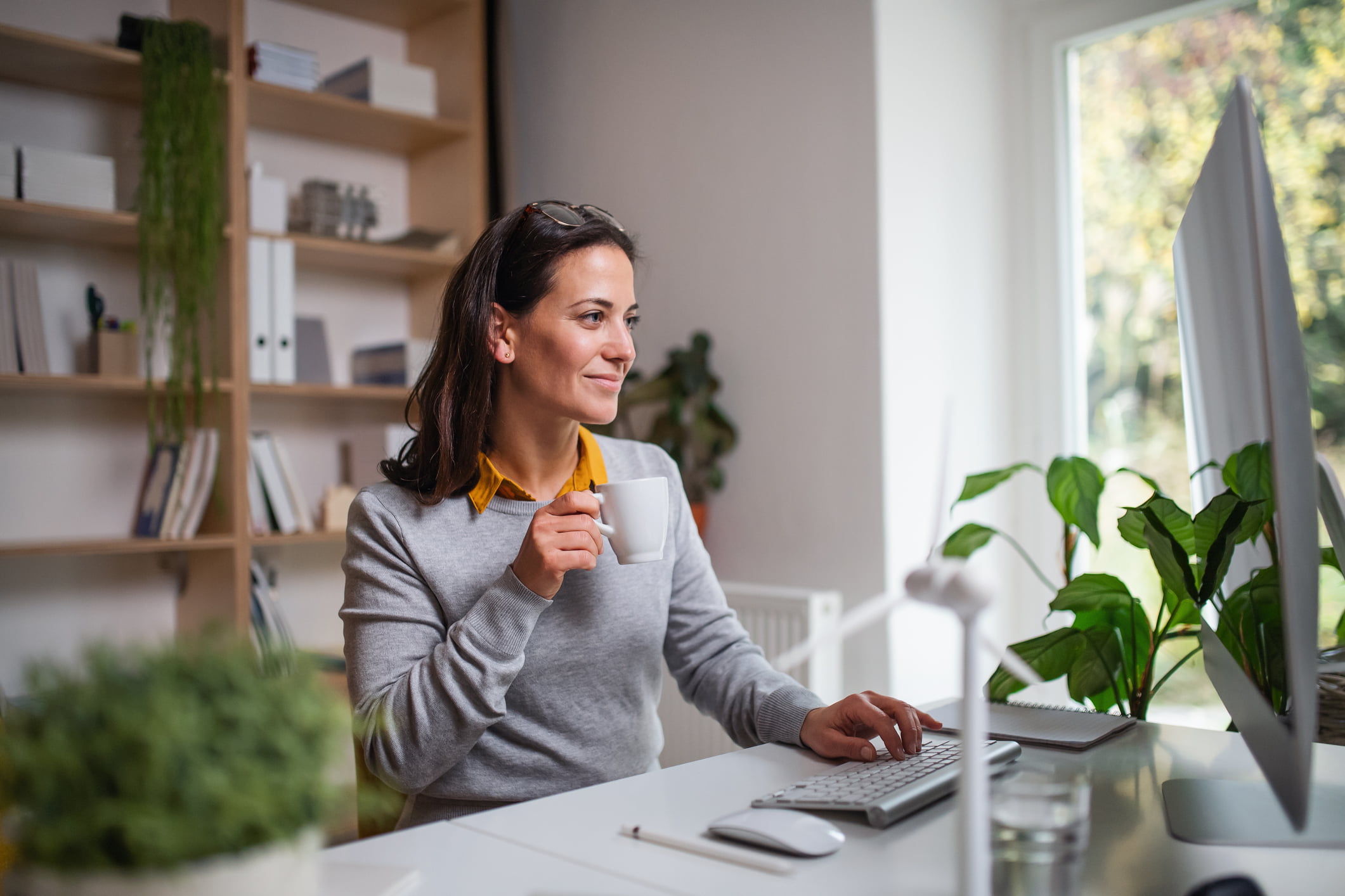 Businesswoman sitting at the desk indoors in office, working with computer.