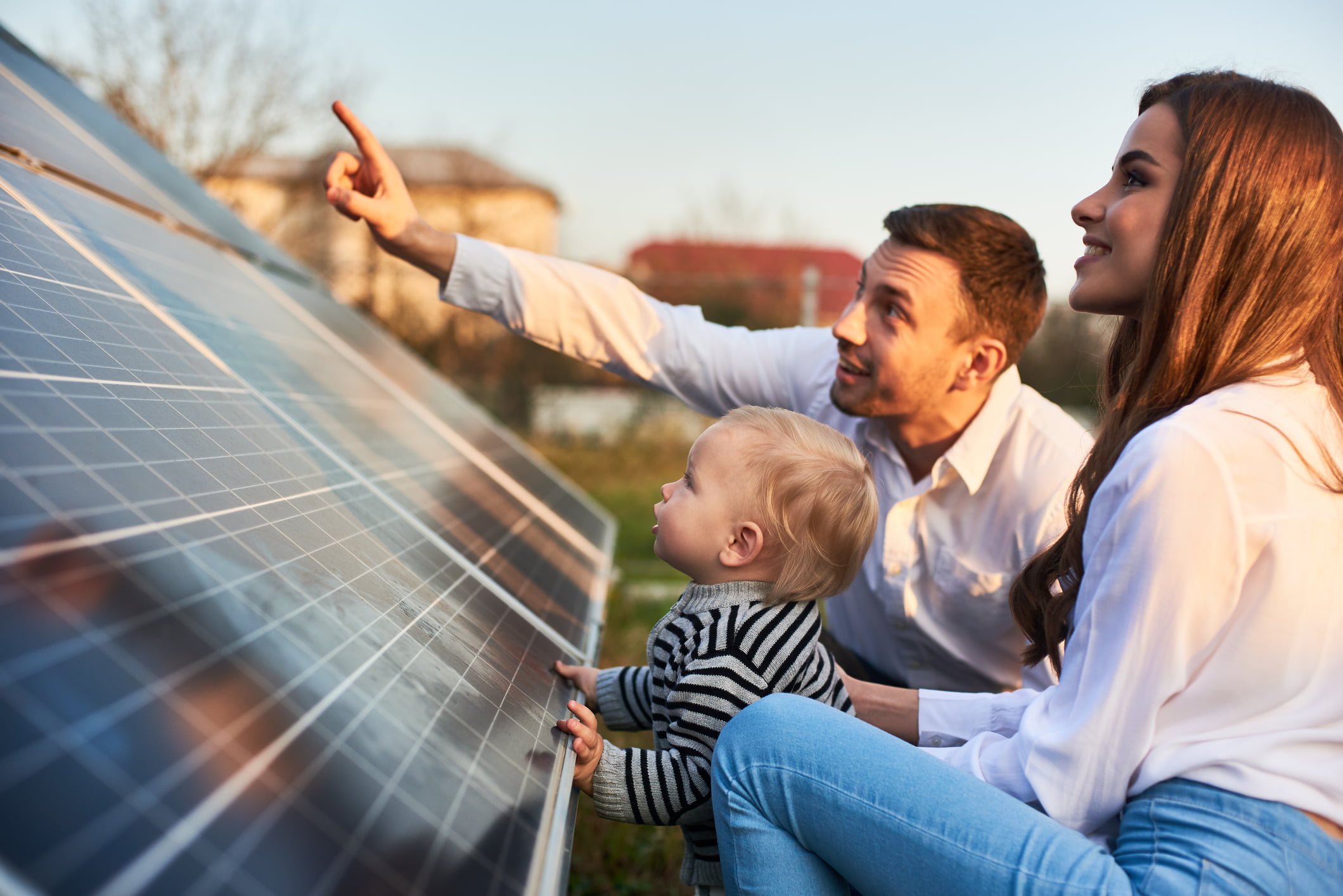 a family look at solar panels on a plot at their house