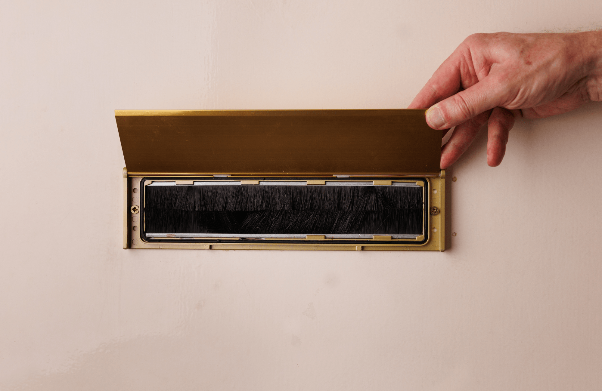 A hand opening a letterbox.