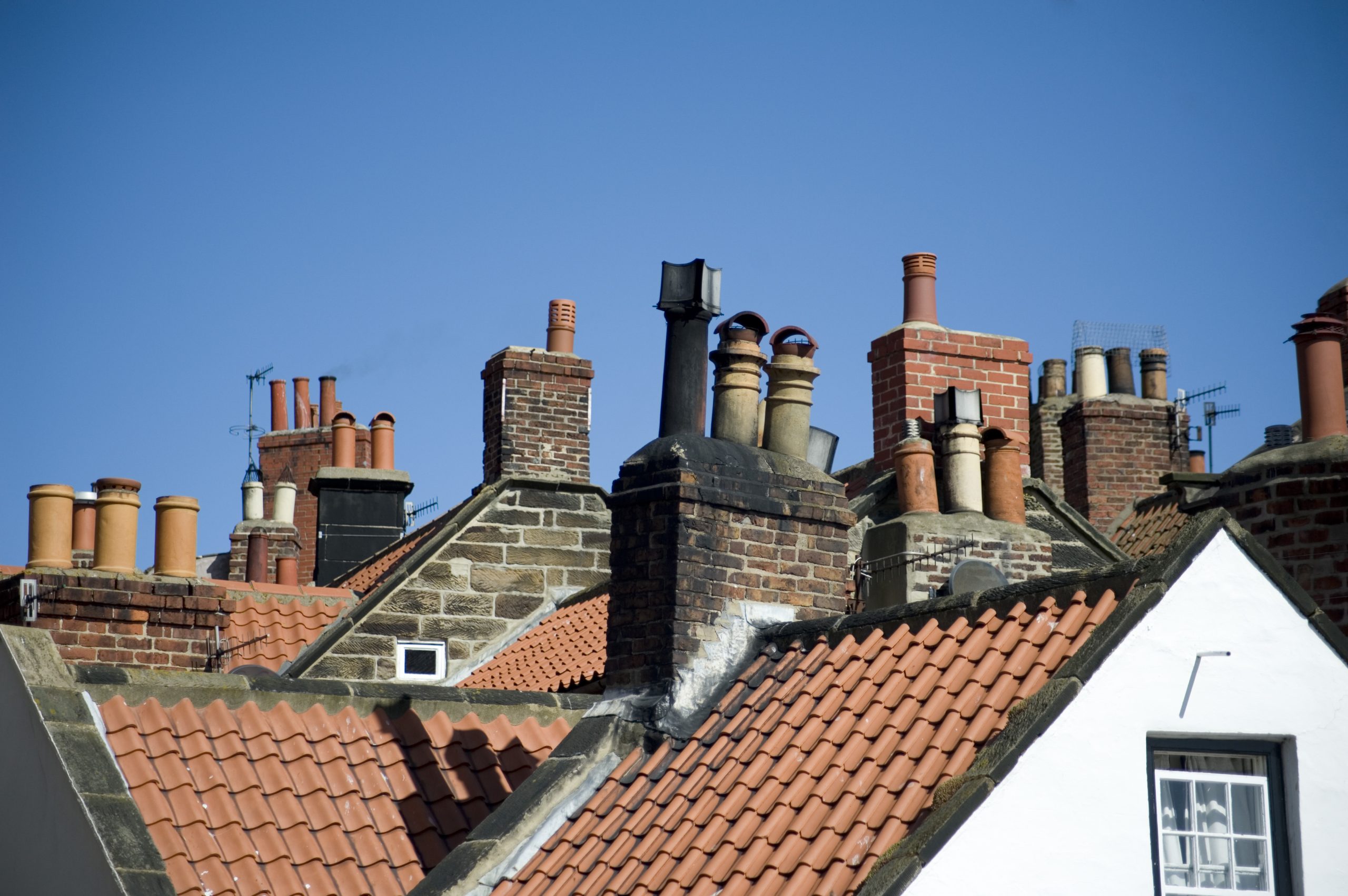 Rooftop view of houses with brick facades and a variety of chimney pots