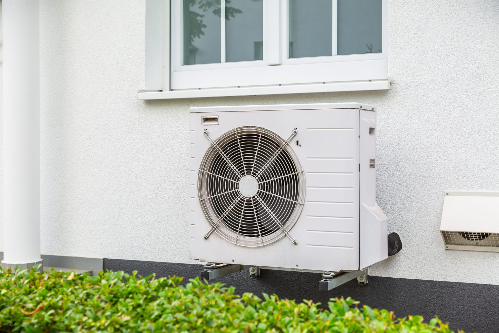 An air source heat pump installed on the outside of a city house.
