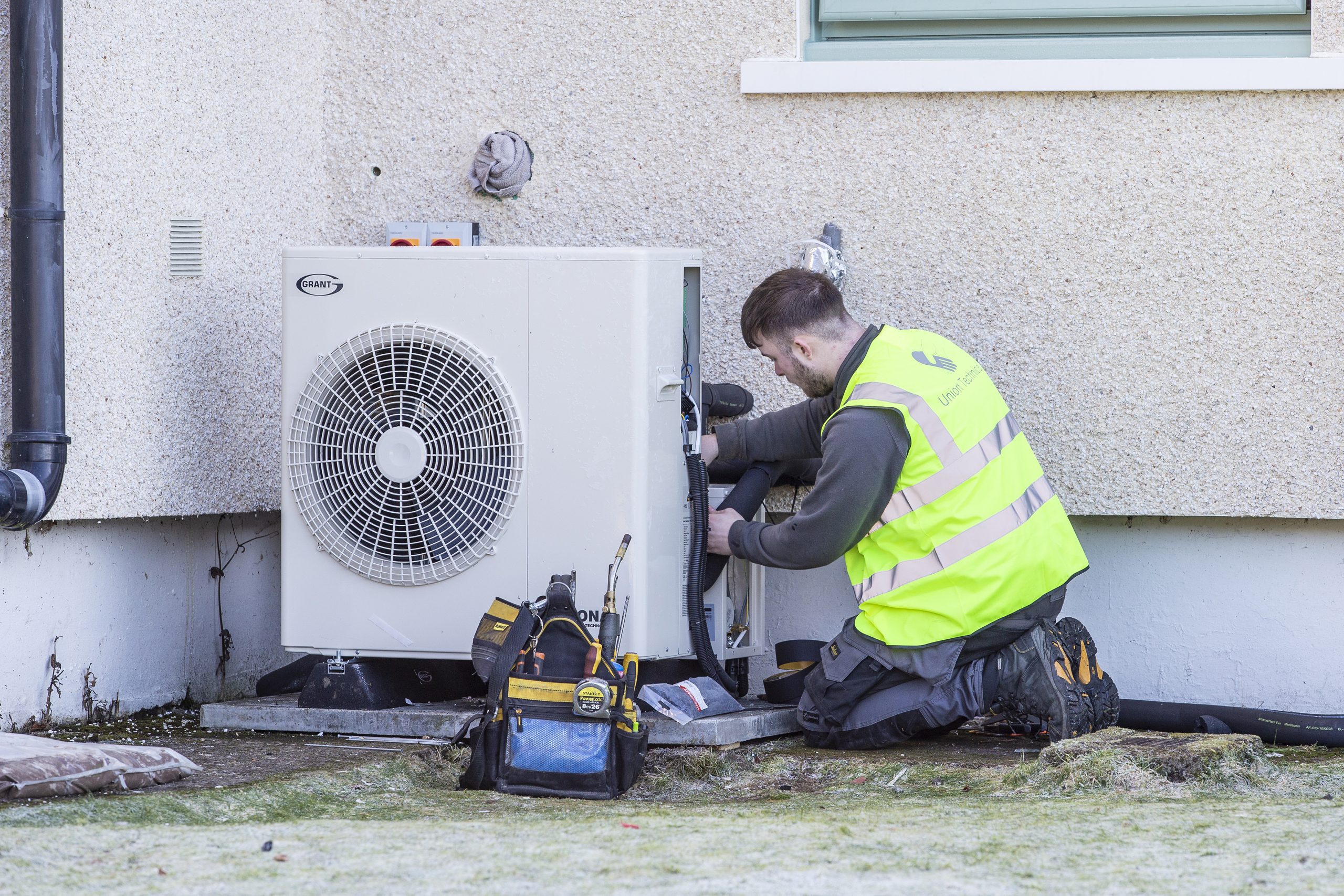installer in high visibility jacket works on heat pump