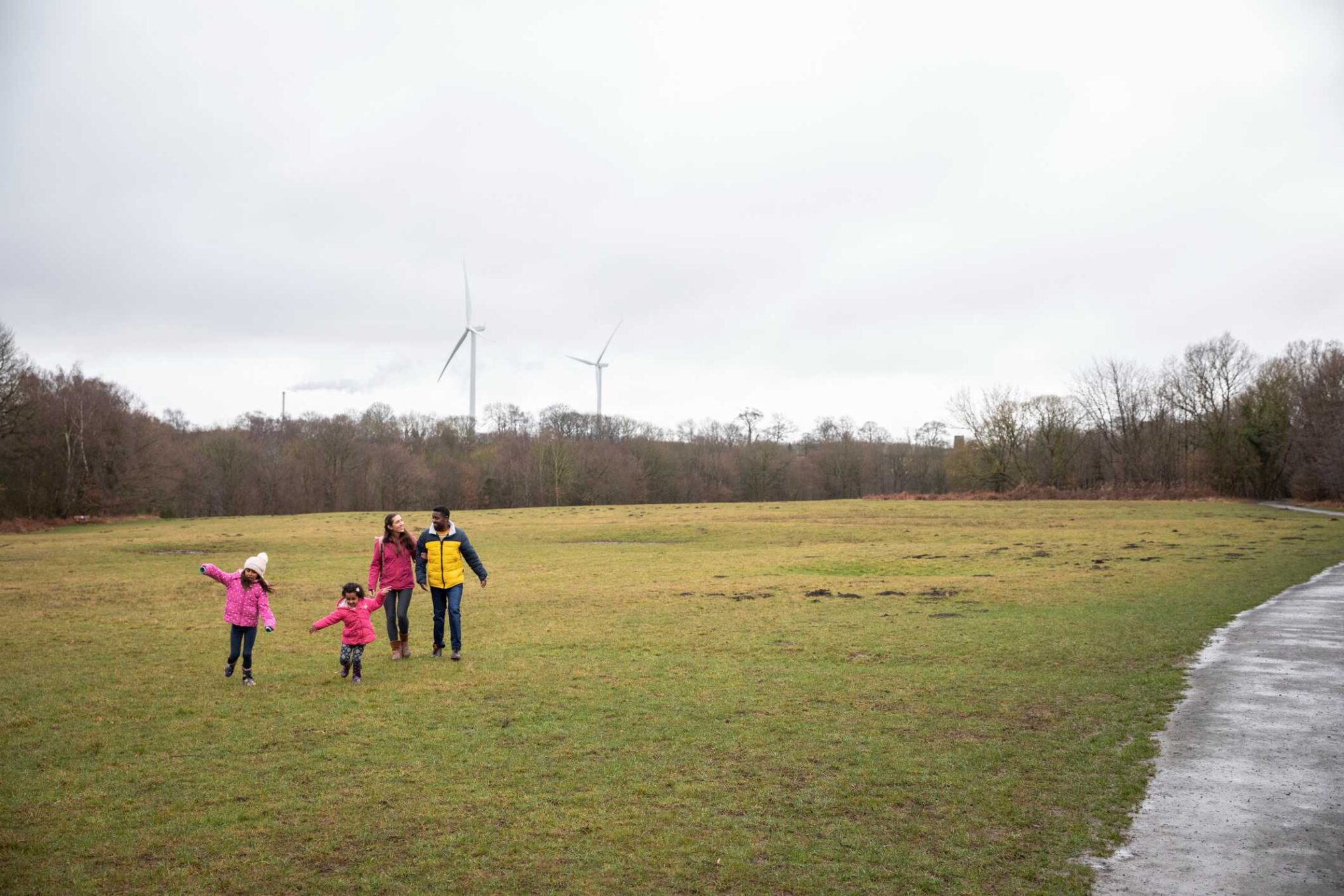 A family walking in a field with wind turbines in the distance