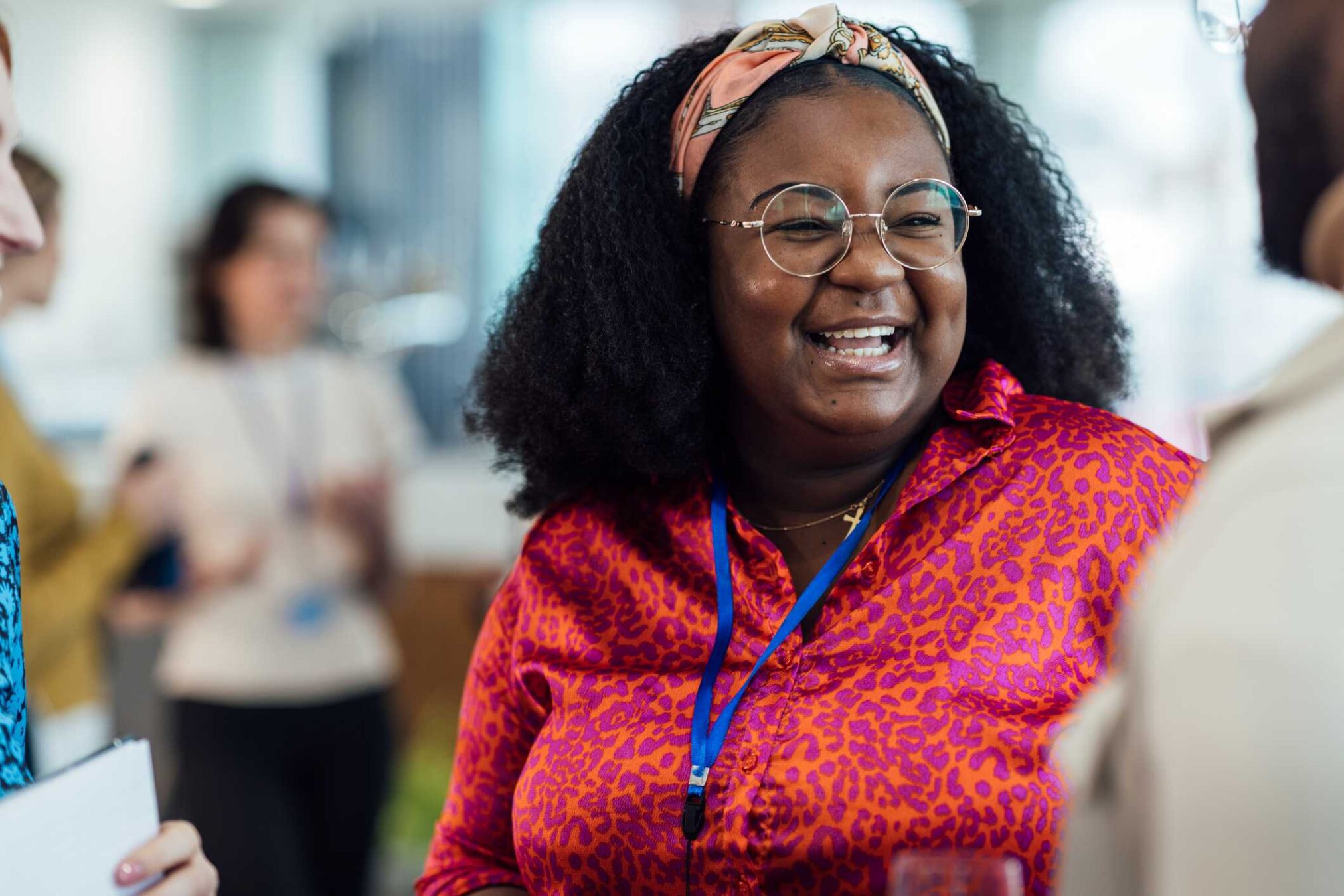 A woman at a business event, smiling while talking to other people