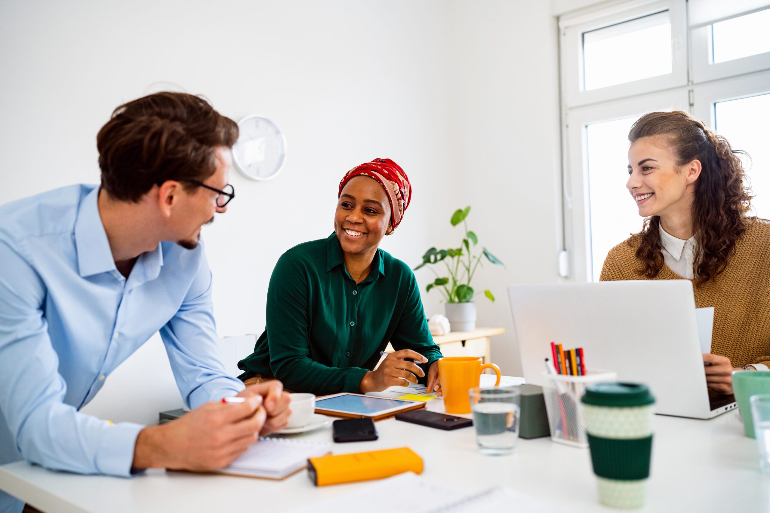 Group of colleagues sitting at a table with a laptop, tablet and notepad in an office