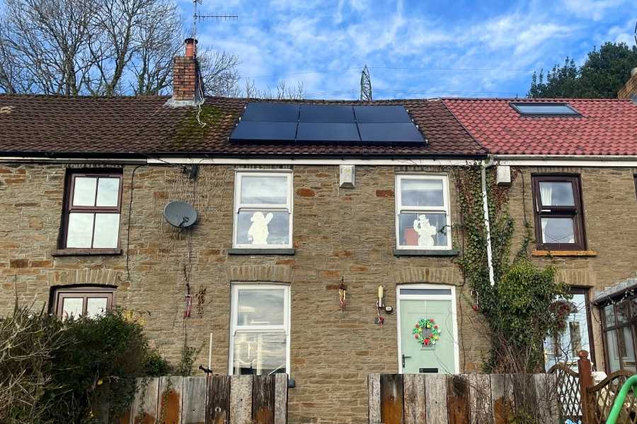 Six solar panels on a 19th -century Welsh cottage with a blue sky in the background.