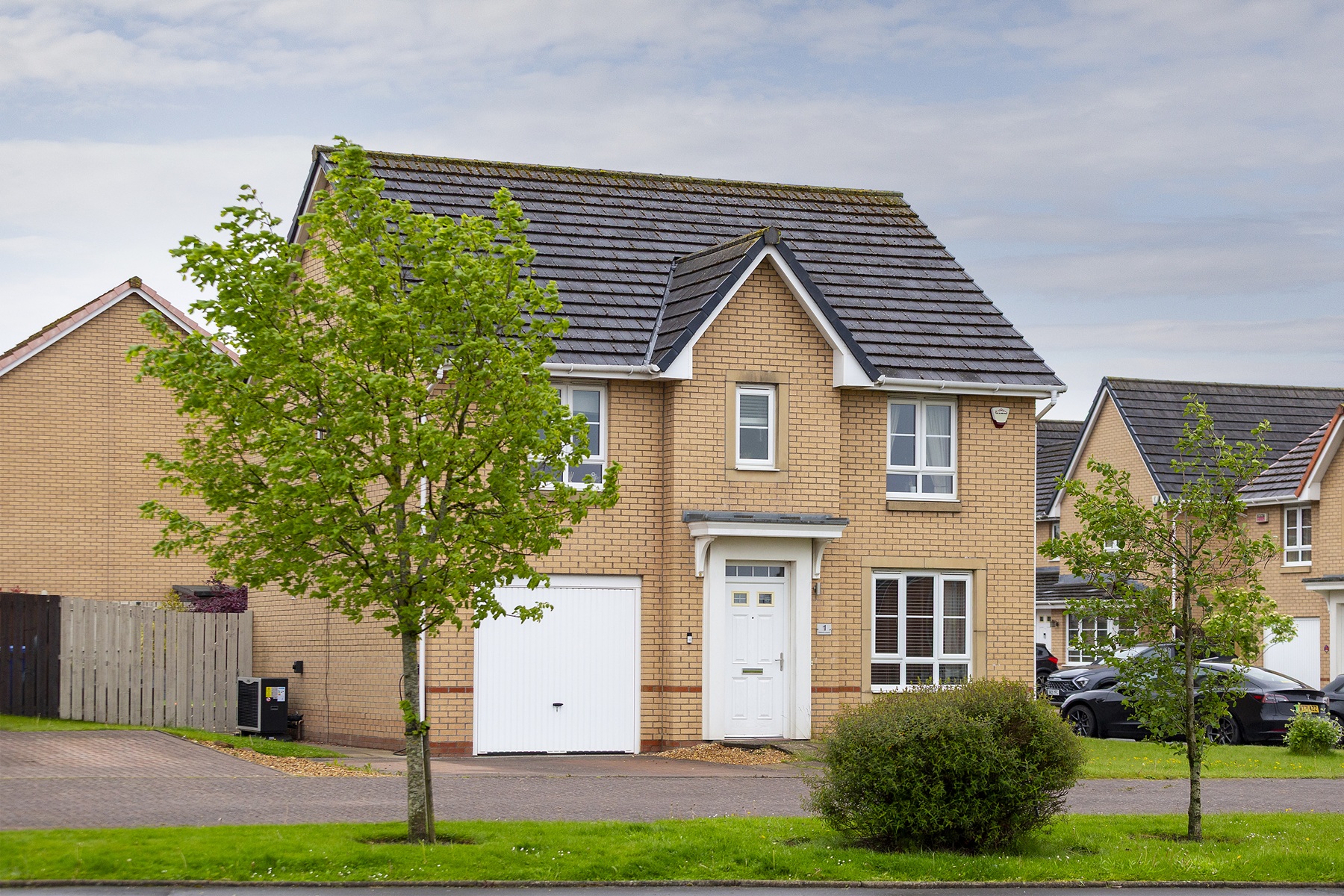 Detached modern home with an outdoor heat pump installed beside the garage.