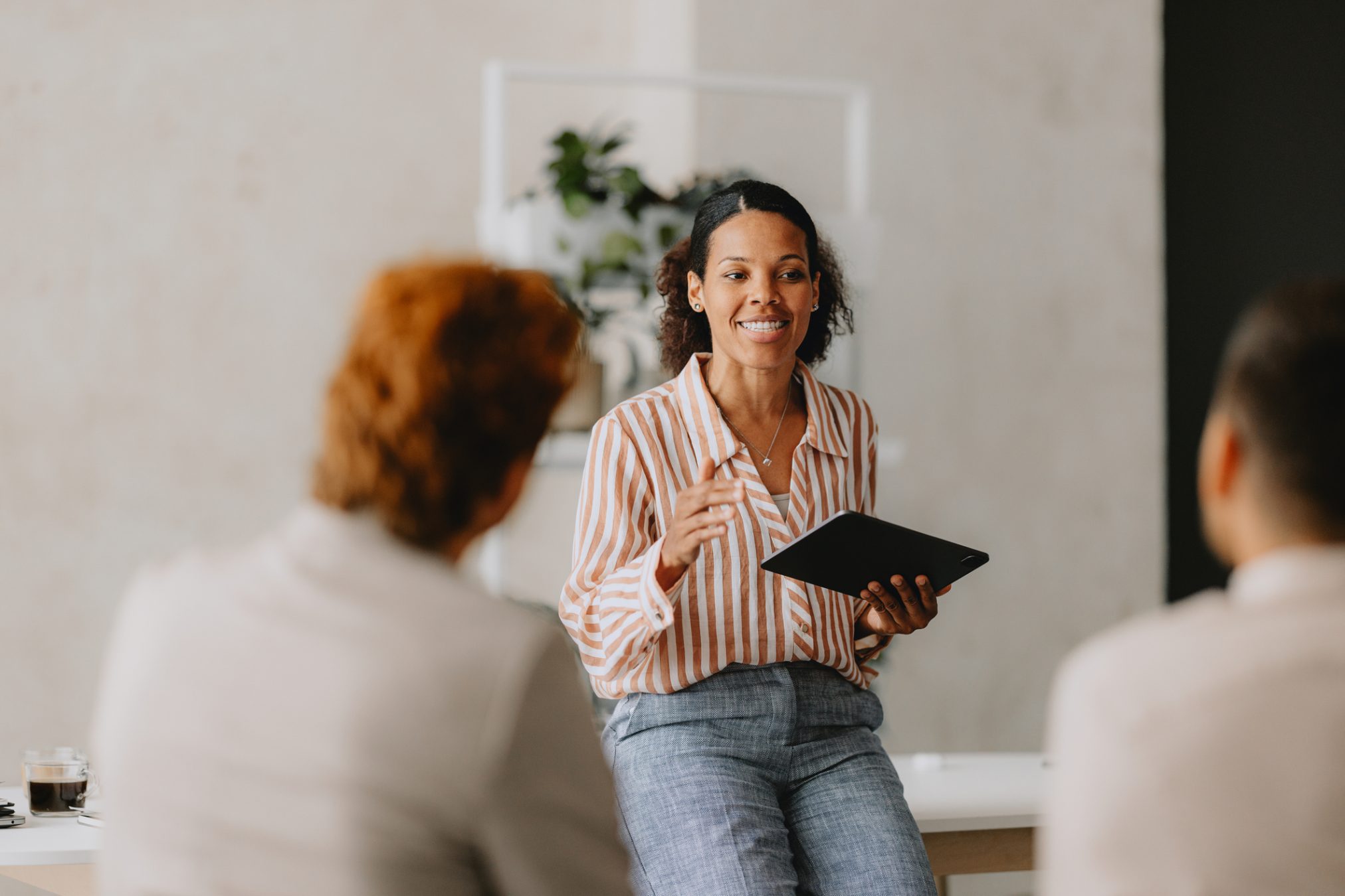 HR professional leading a group business meeting at a bright beige office. 