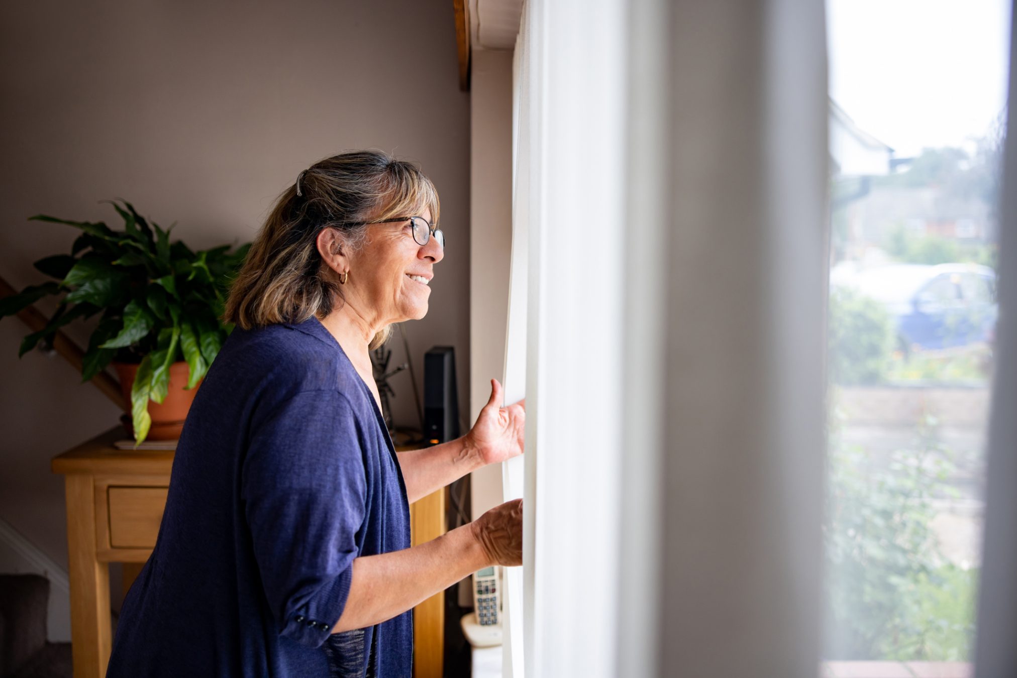 Woman at home looking through the window.